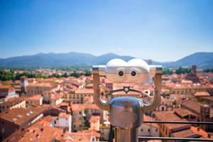 telescópio turístico olha para a pequena cidade italiana. fechar binóculos de metal no ponto de vista de fundo com vista para a montanha foto