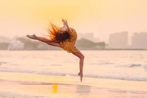 adorável menina feliz na praia branca ao pôr do sol. foto