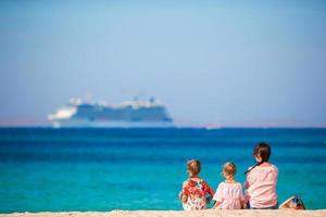 família na praia relaxar e olhar para o horizonte. mãe e filhos aproveitam férias na europa foto