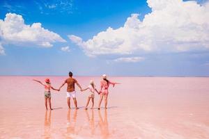 família caminha em um lago de sal rosa em um dia ensolarado de verão. foto