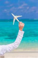 jovem com miniatura de um avião na praia tropical foto