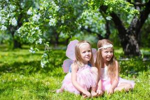 adoráveis meninas no jardim de macieiras em flor na primavera foto