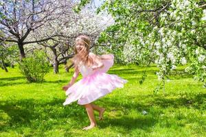 menina adorável divirta-se no jardim de macieiras em flor foto