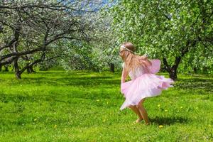 menina adorável divirta-se no jardim de macieiras em flor foto