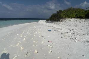 lixo na praia de areia paradisíaca de ilha tropical foto