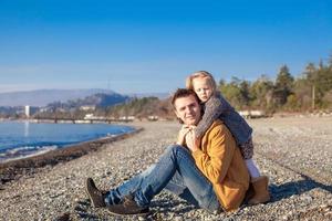 jovem pai e filha na praia em um dia ensolarado de inverno foto