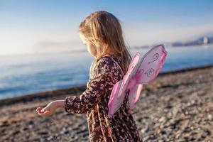 adorável menina se divertindo na praia em um dia ensolarado de inverno foto