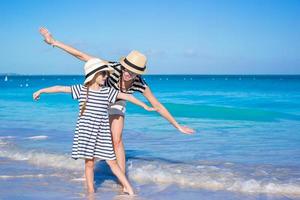 jovem linda mãe e sua adorável filha se divertem na praia tropical foto