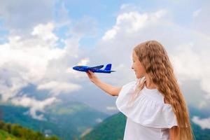 menina feliz com avião de brinquedo nas mãos nas montanhas foto
