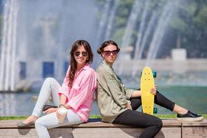 retrato de jovens urbanas felizes na cidade europeia. turistas caucasianos fundo a grande fonte com skate ao ar livre foto