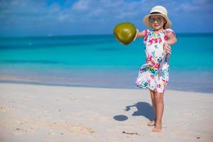 menina adorável com coco na praia branca durante as férias de verão foto