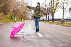 jovem andando com guarda-chuva em dia chuvoso de outono foto