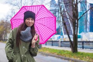 jovem andando com guarda-chuva em dia chuvoso de outono foto