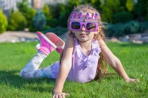 menina adorável em óculos de feliz aniversário sorrindo ao ar livre foto