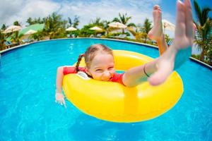 retrato de criança feliz com círculo de borracha inflável se divertindo na piscina foto