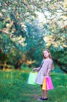 adorável menina andando com sacolas de compras ao ar livre foto