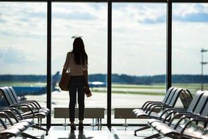 silhueta de mulher em um saguão de aeroporto esperando por aeronaves de voo foto