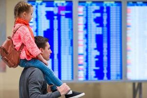 menina com seu pai informações de voo de fundo no aeroporto foto