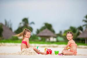 meninas bonitas brincando com brinquedos de praia durante as férias tropicais foto