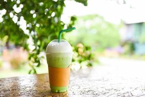 smoothie de chá verde - chá verde matcha com leite em vidro plástico sobre a mesa de madeira e fundo verde natural foto