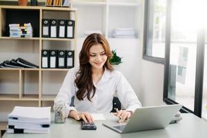 mulher de negócios trabalhando no escritório de mesa com o uso de uma calculadora para calcular os números, conceito de contabilidade financeira foto