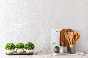 fundo de cozinha moderna com utensílios ecológicos e plantas em vasos de cerâmica em uma bancada de mármore branco. uma cópia do espaço. foto