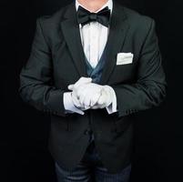 retrato de mordomo de terno escuro e luvas brancas ansioso para servir. conceito de indústria de serviços e hospitalidade profissional. foto