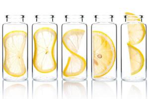 fatia de limão de cuidado de pele caseiro e torção de limão em garrafas de vidro isoladas no fundo branco. foto
