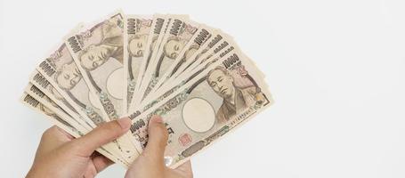 mão de homem segurando a pilha de notas de iene japonês. dinheiro de mil ienes. dinheiro do japão, impostos, economia de recessão, inflação, investimento, finanças e conceitos de pagamento de compras foto