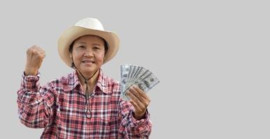 mulher asiática idosa isolada nos mantém notas de dólar na mão com um belo sorriso no rosto alegremente com caminhos de recorte. foto