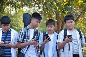 foco suave jovens adolescentes asiáticos mostrando seus próprios telefones celulares para seus amigos durante a caminhada de volta para casa depois de fazer aulas de música e fazer trabalhos de projeto escolar na escola juntos. foto