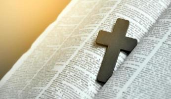 cruz de madeira closeup no livro da Bíblia, foco suave e seletivo. foto