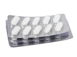 pílulas brancas ovais em um blister cinza sobre um fundo branco foto
