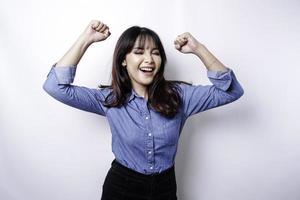 uma jovem mulher asiática com uma expressão de sucesso feliz vestindo camisa azul isolada por fundo branco foto