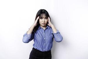 um retrato de uma mulher asiática vestindo uma camisa azul isolada por um fundo branco parece deprimido foto