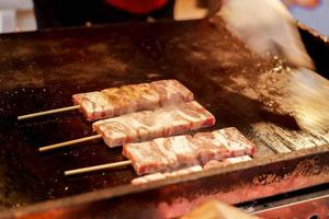 closeup churrasco kobe vara de carne na panela quente. um dos lanches populares para turistas no mercado de kuromon, cidade de osaka, japão foto