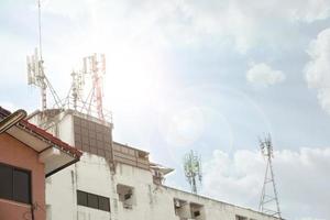 torre de comunicação com antenas de vários tamanhos no topo do edifício no céu azul brilhante com fundo de nuvens. foto