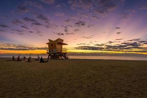 nascer do sol em uma das famosas casas de guarda de elevador em miami beach, florida, eua com uma equipe de ioga fazendo exercícios foto