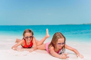 duas meninas felizes se divertem muito na praia tropical brincando juntas foto