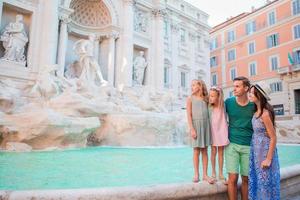 família perto de fontana di trevi, roma, itália. pais e filhos felizes desfrutam de férias italianas na europa. foto