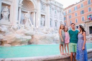 família perto de fontana di trevi, roma, itália. pais e filhos felizes desfrutam de férias italianas na europa. foto