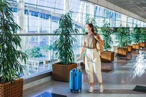mulher jovem turista em máscara médica com bagagem no aeroporto internacional foto