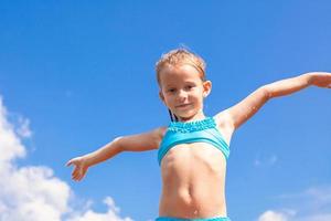 adorável menina abriu os braços fundo do céu azul foto