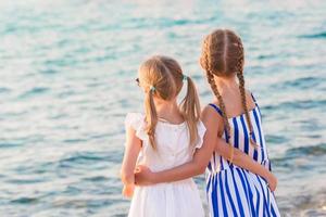 meninas adoráveis em Little Venice, a área turística mais popular da ilha de Mykonos, Grécia. a visão traseira de crianças bonitas olha para o fundo de pequena veneza. foto