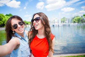 garotas caucasianas fazendo fonte grande de fundo de selfie. jovens amigos turistas viajando de férias ao ar livre sorrindo felizes. foto