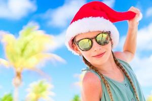 retrato de menina com chapéu de Papai Noel durante as férias na praia de natal foto