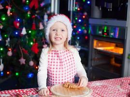 retrato de uma menina adorável na cozinha assando pão de gengibre foto