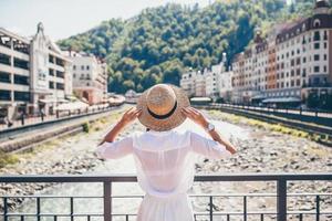 garota feliz no chapéu na margem de um rio de montanha em uma cidade europeia. foto