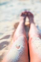 close-up de pés femininos na praia de areia branca foto