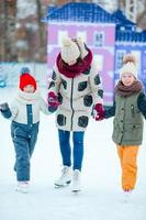 família patinando na pista de gelo. mãe e filhos aprendendo a patinar no inverno foto